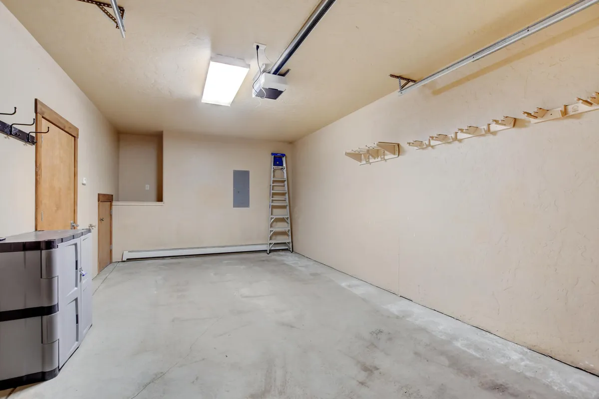 A practical garage interior with empty space, a ladder, and storage bins, ready for ski gear and vehicle parking. The focus is on functionality and organization, supporting active mountain living.